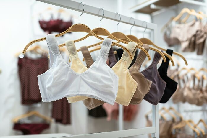 Luxury bras on wooden hangers in a boutique, showcasing expensive items worth spending money on.