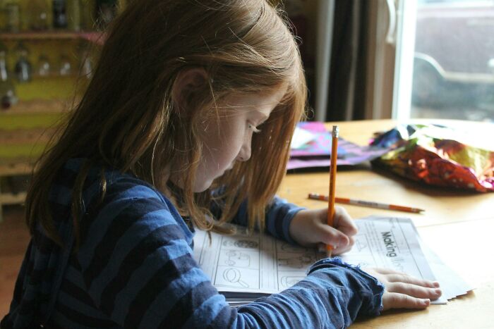 Child drawing at a table, representing millennials' challenges in growing into adulthood.