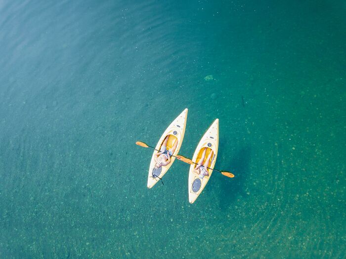 Two people kayaking on clear water.