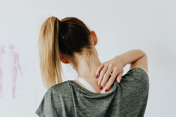 Woman with a ponytail touching her neck, representing common discomfort or issues for older adults.