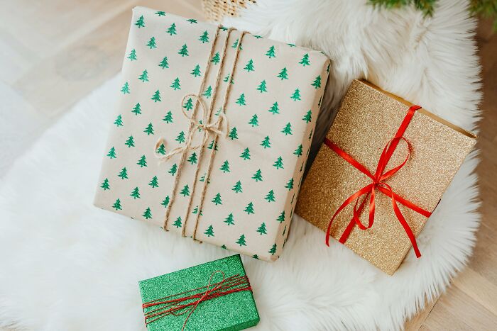 Gifts wrapped in festive paper on a cozy white rug, representing items becoming unaffordable for the middle class.