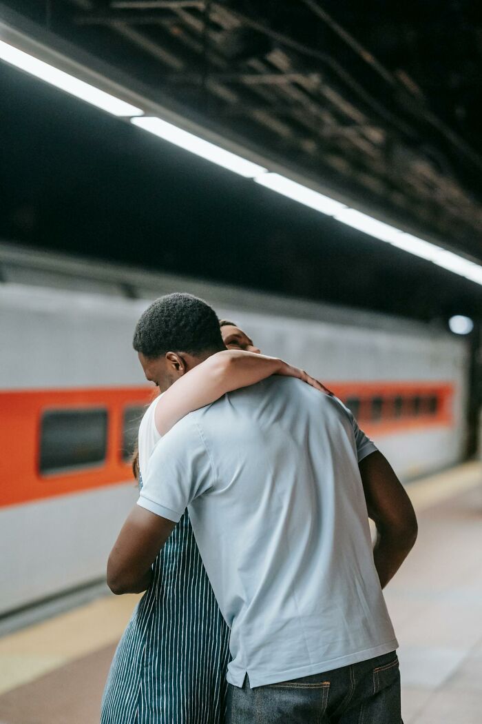 Couple embracing in a train station, highlighting changing social norms.