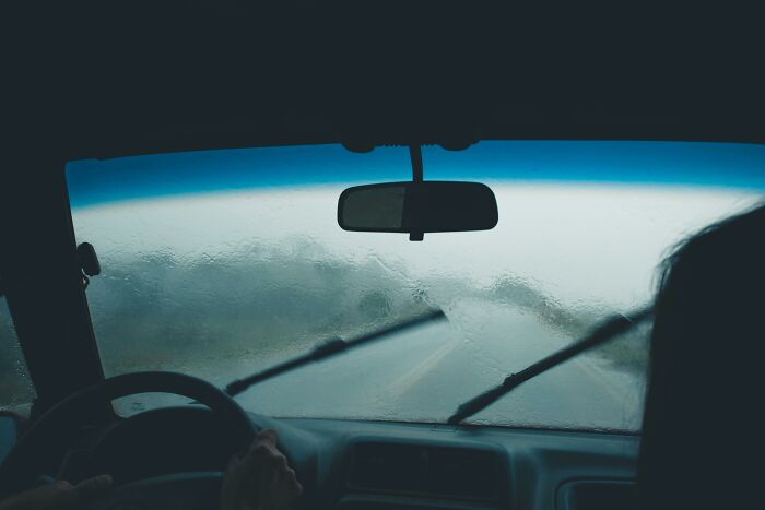 Driving through heavy rain, blurry road view, invoking a creepy and unsettling feeling.