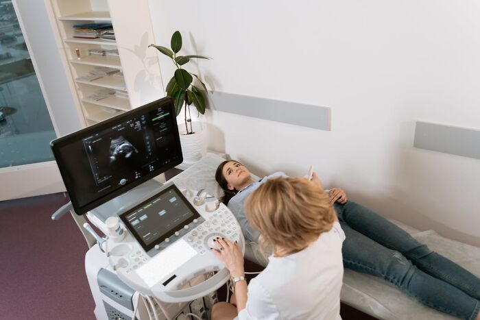 Person lying on examination table during ultrasound, highlighting normalized medical practices.