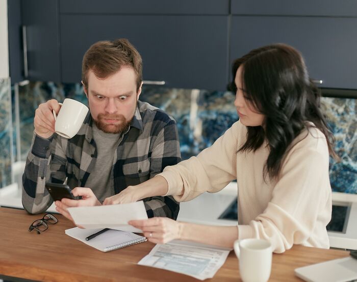 Man looking shocked at a document while holding a phone, woman pointing at it, representing an unethical life hack scenario.