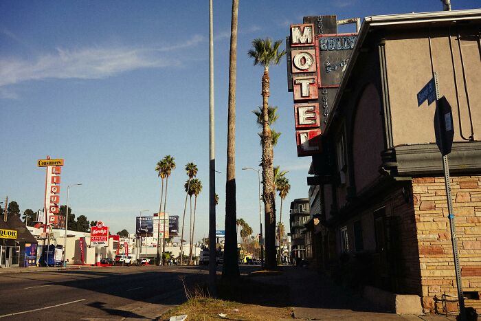 Vintage motel sign on a sunny street, contributing to a creepy aesthetic.