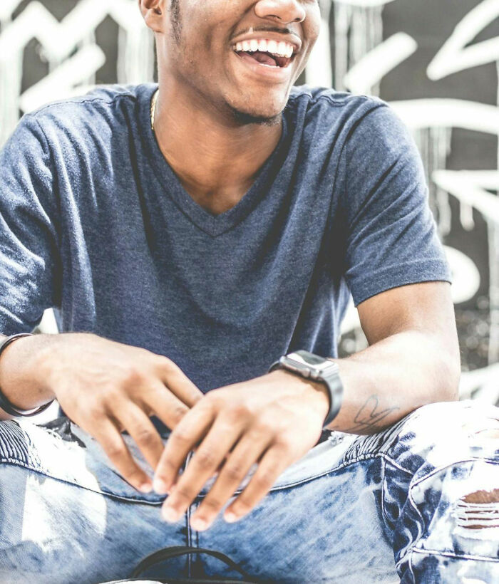 Man wearing jeans and a gray t-shirt smiling, representing happiness in challenging social norms.