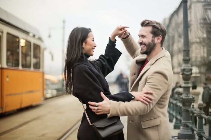 A man playfully dancing with a woman on a city street, showcasing non-sexual things men do that attract women.