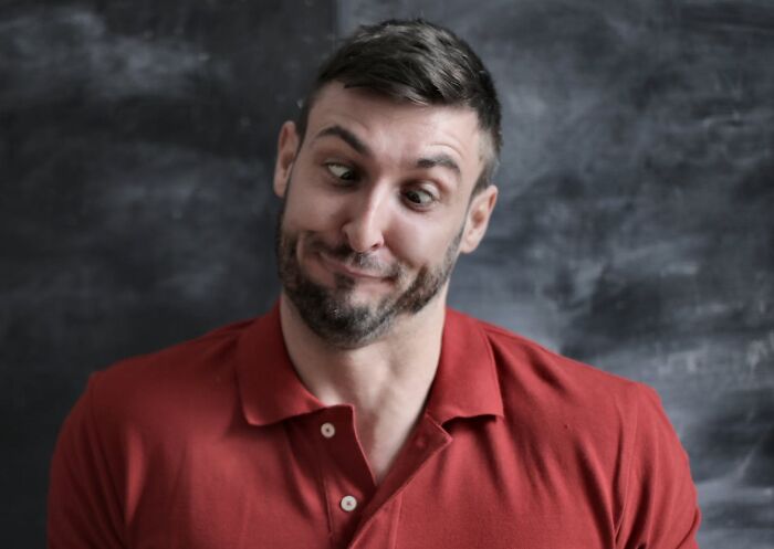 Man in a red shirt making a funny expression, illustrating one of the non-sexual things men do that attract women.