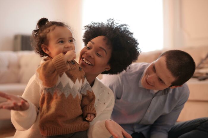 Child with parents in cozy living room, illustrating kids feeling like foreigners in a different country.