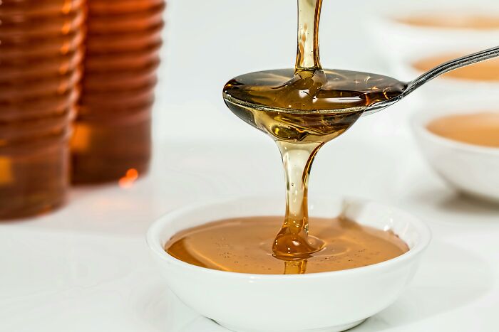 Pouring honey into a white bowl, showcasing a peculiar natural behavior.