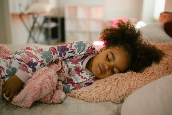 Child peacefully sleeping, clutching a stuffed animal, in a cozy setting.