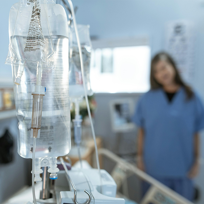 IV drip in a hospital setting with a blurred person in scrubs, highlighting NICU equipment.