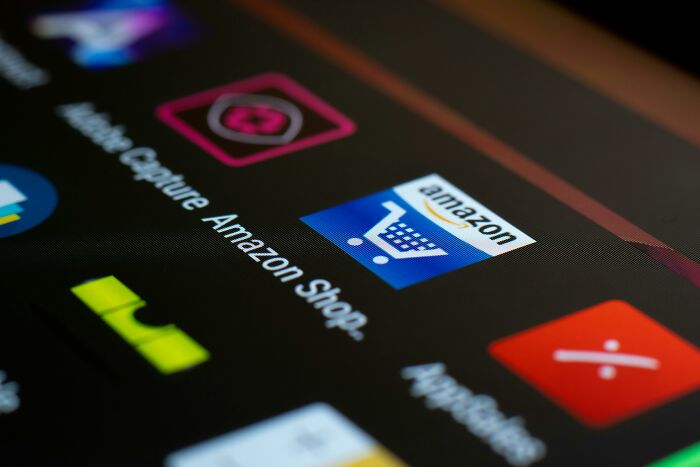 Close-up of a smartphone screen displaying the Amazon shopping app icon, related to unethical life hacks.