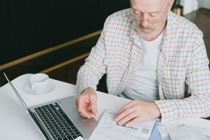 A man in a plaid shirt reviewing documents at a laptop, illustrating a savage job exit strategy.