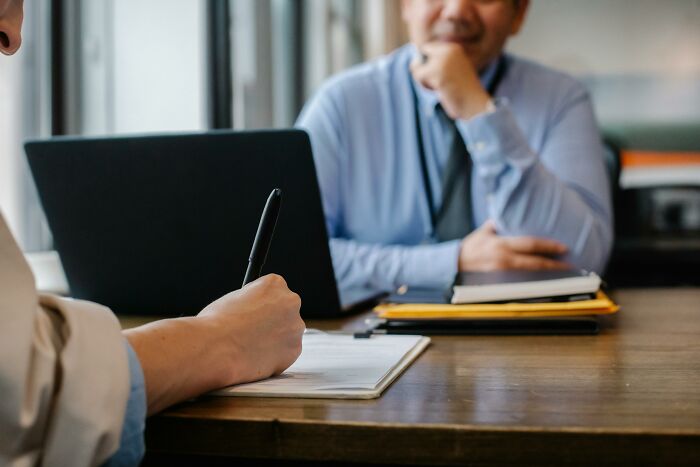 Person writing notes during a job interview, highlighting potential resume red flags.