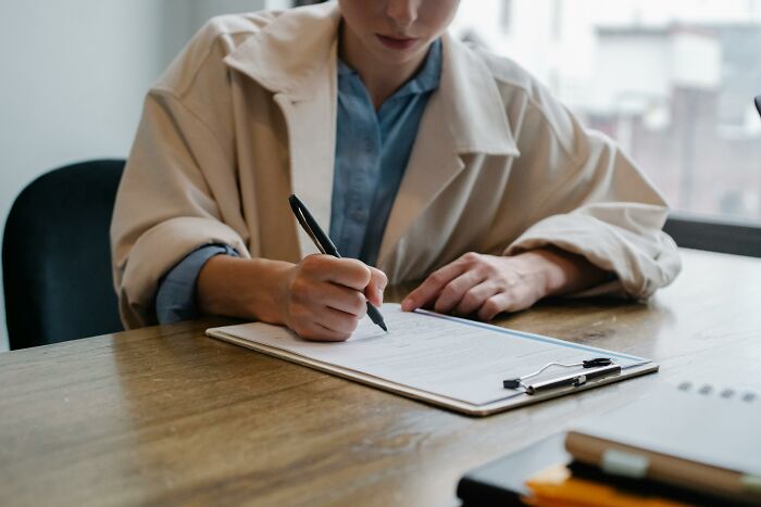 Person reviewing a resume, highlighting HR red flags on a wooden desk with a clipboard.