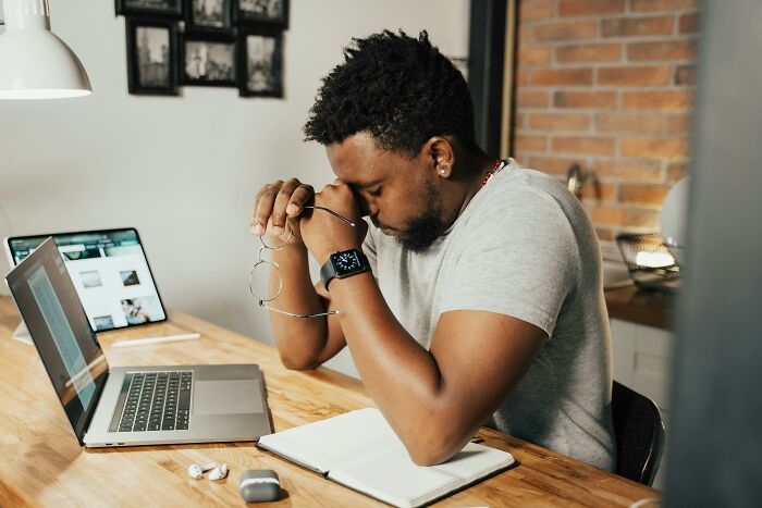 Man sitting at a desk with laptop and notebook, contemplating an unethical life hack.