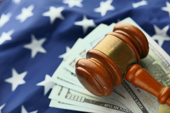 Gavel on dollar bills against a star-spangled backdrop, symbolizing legal and financial challenges for millennials.