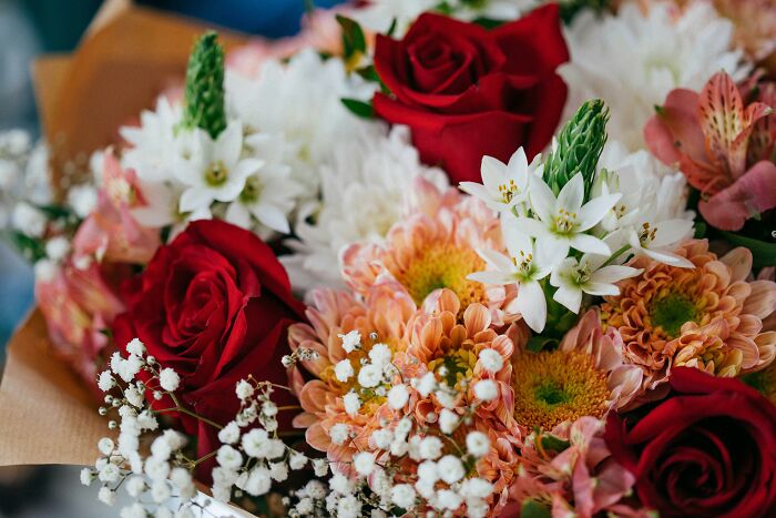 A vibrant bouquet of red roses, white flowers, and orange blossoms arranged together.