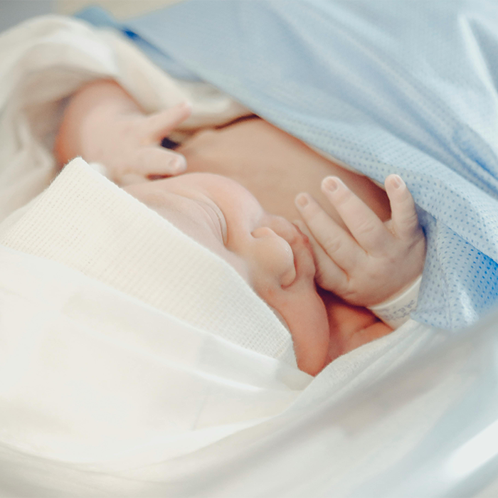 Newborn baby wrapped in a blanket lying in the NICU, emphasizing the NICU environment.