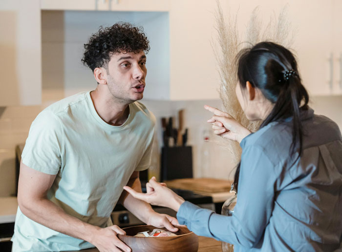 Couple having a discussion in a kitchen about posting political content, highlighting themes of career and censorship.