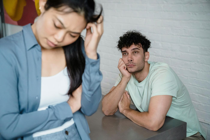 Couple in discussion about political posts online, woman looks concerned, while man appears thoughtful.