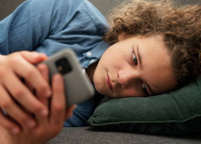 Person using a smartphone, reflecting on the post-brain rot era while lying down on a pillow.