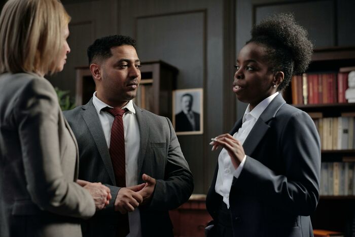 Three professionals engaged in discussion, possibly applying psychological tricks in an office setting.