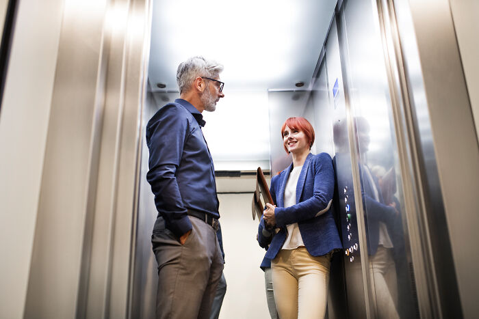 Two people having a conversation in an elevator, illustrating interesting psychological tricks in social interactions.