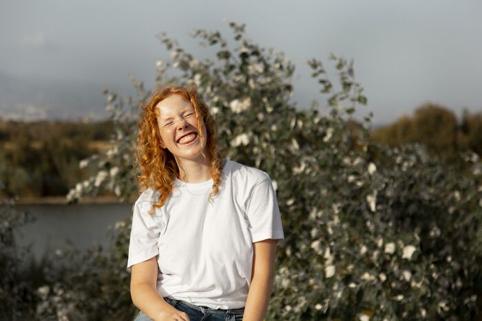 Smiling woman in a white shirt sitting outdoors, illustrating psychological tricks that influence people.