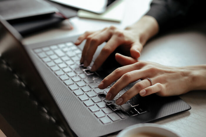 Hands typing on a laptop keyboard, illustrating psychological tricks in communication.