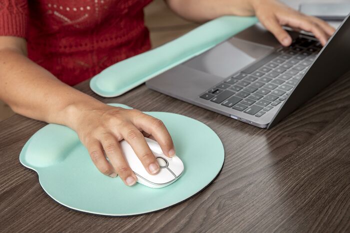 Person using a laptop with ergonomic mouse pad, illustrating psychological tricks for productivity.