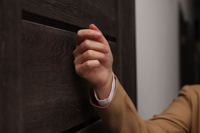 A hand knocking on a wooden door, illustrating psychological tricks and their impact on people.