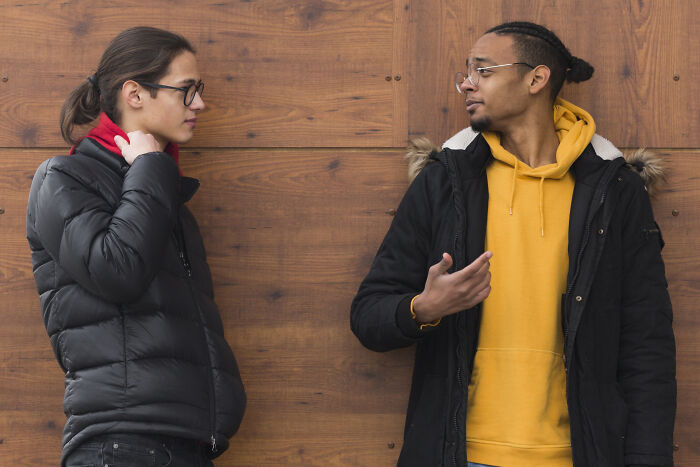 Two people conversing, illustrating psychological tricks in communication against a wooden background.