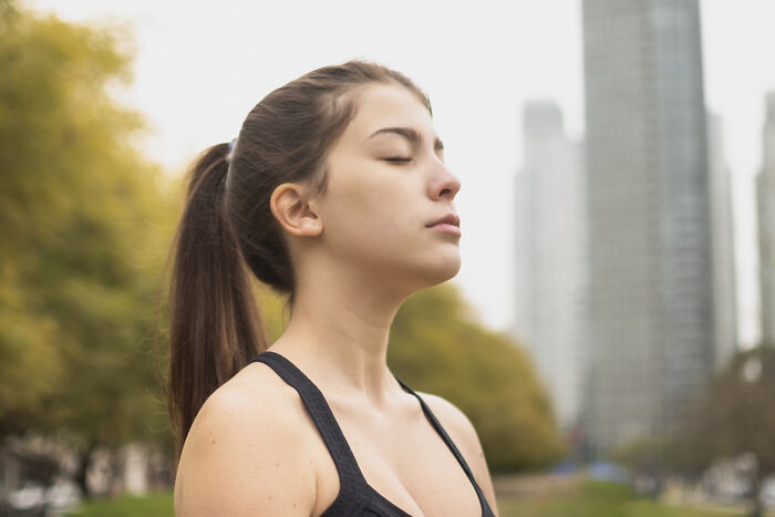 A woman practicing a psychological trick by meditating in an urban park setting.