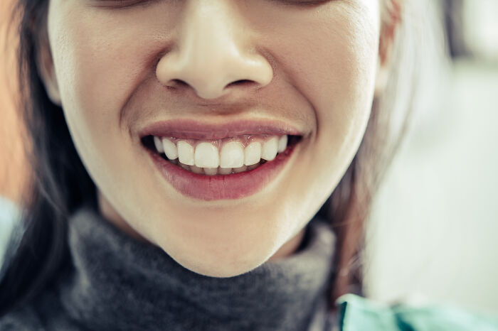 Close-up of a woman smiling, demonstrating psychological tricks for better social interactions.