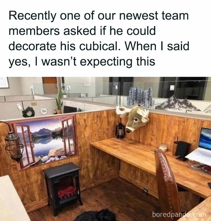 A hilariously random cubicle decorated like a cozy cabin with a faux fireplace and a moose head.