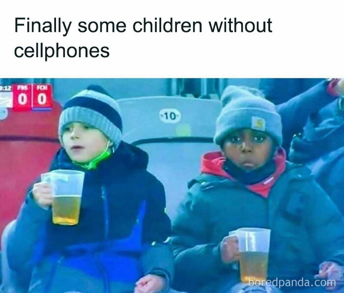 Two kids at a sports event, bundled up, holding cups, illustrating a random meme.