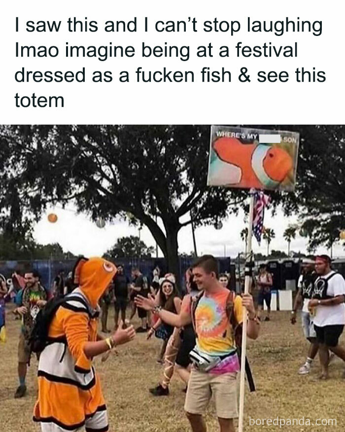 Festival attendee in a fish costume spots a funny totem pole, bringing hilariously random meme vibes.