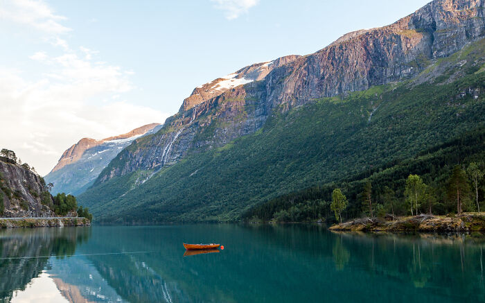 Scenic view of a serene lake surrounded by mountains in the Tuscany region of Italy, featuring a small orange boat.