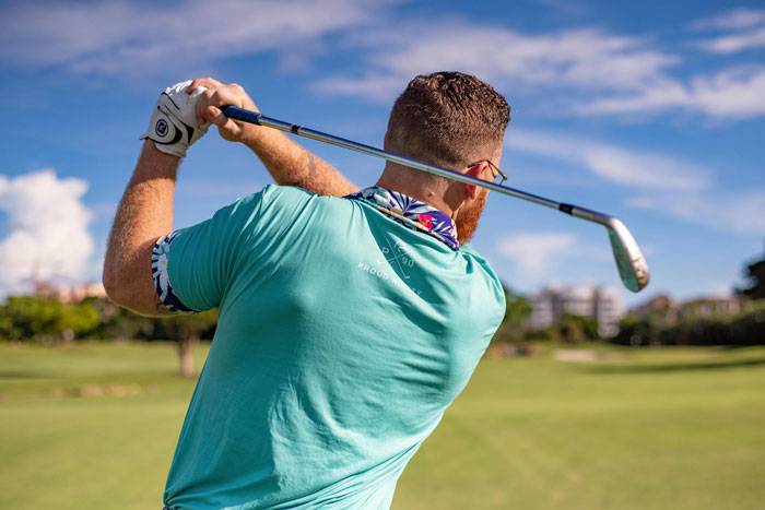 Man swinging a golf club on a sunny day, focusing on hobbies.