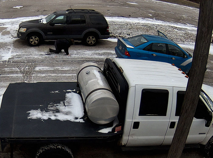 A scene involving road rage in a snowy parking lot with parked vehicles and a person on the ground.