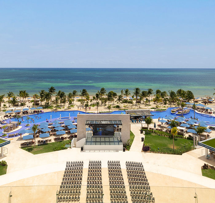 Aerial view of a Cancun resort with beachside pool and palm trees.