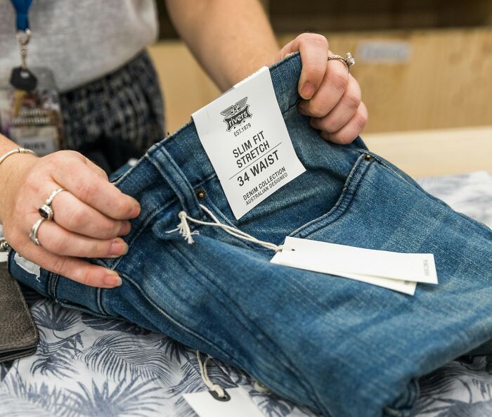 Hands holding premium jeans labeled "Slim Fit," an example of expensive items worth spending money on.