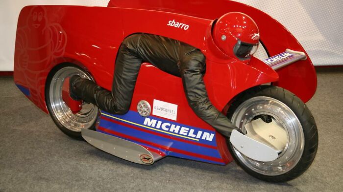 Futuristic motorcycle design from historical inventions display, featuring red bodywork and Michelin branding.