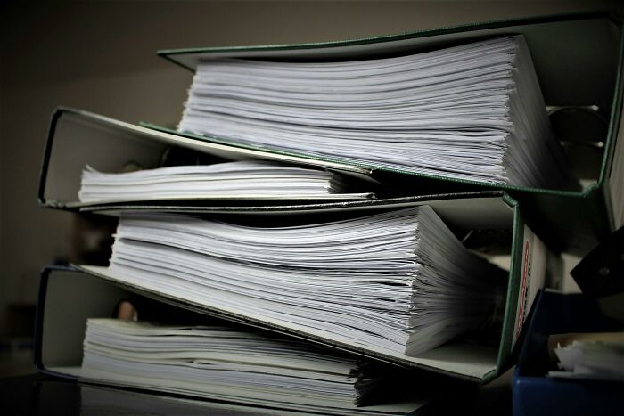 Stack of binders filled with documents to help protect your info against home title hijacking by scammers.