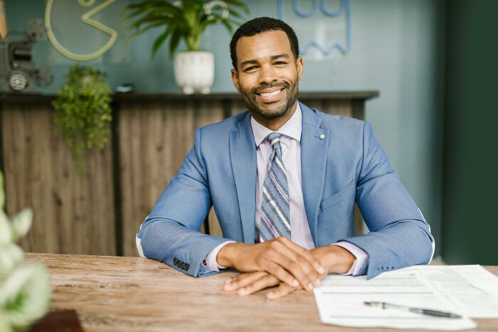 Man in a blue suit sitting at a desk, discussing ways to protect your info from scammers.