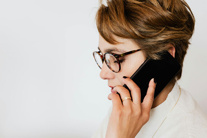 A woman with glasses discusses wedding color schemes on her phone.