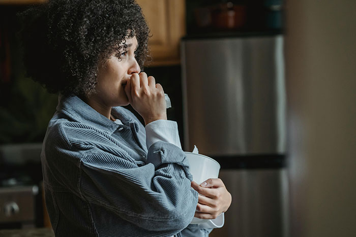 A woman looking pensive in a kitchen, embodying wedding color scheme drama.